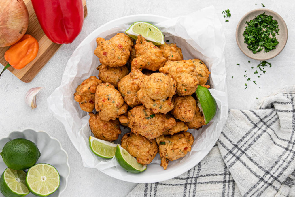 Saltfish fritters on parchment with lime wedges ready to serve
