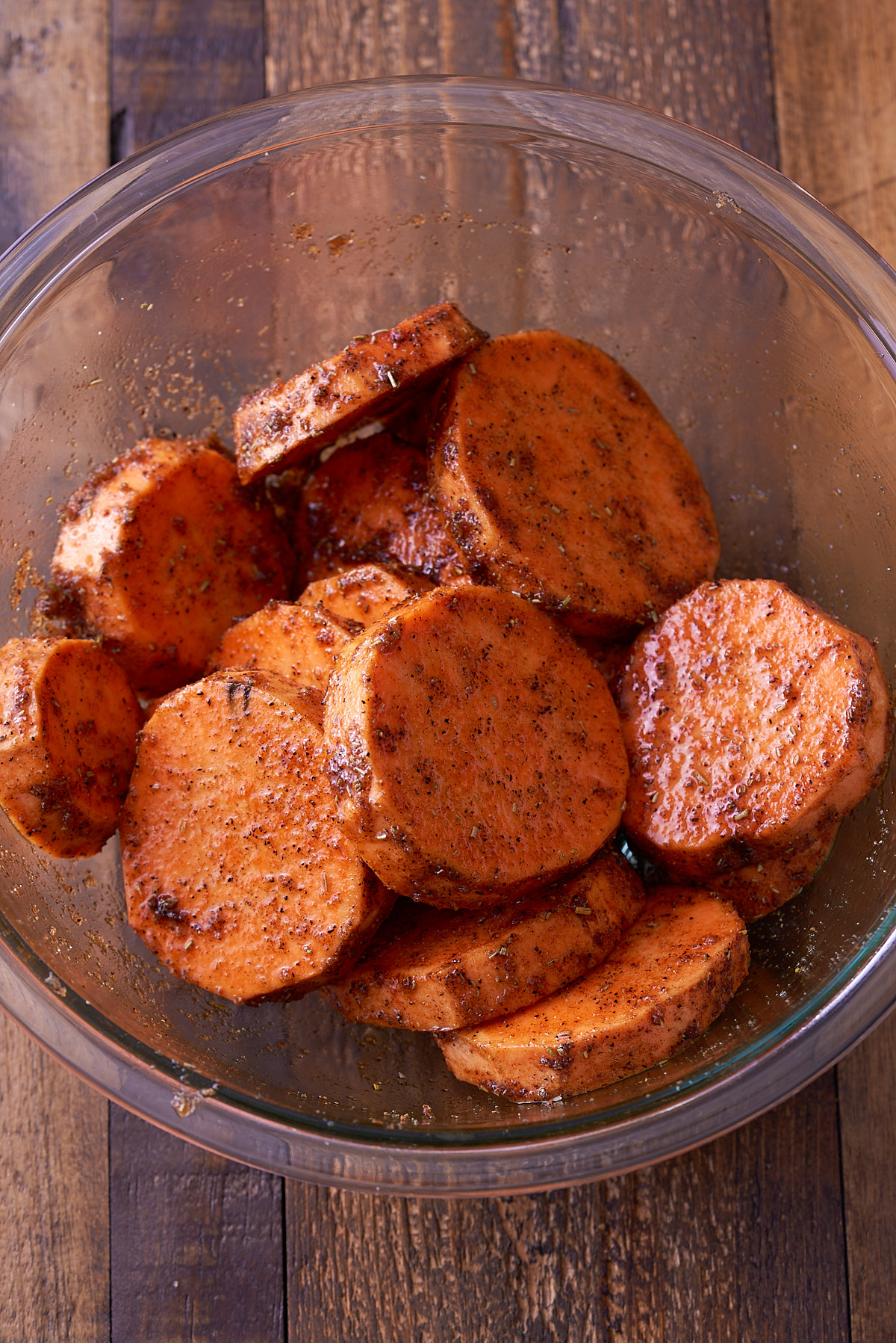 sliced sweet potato in glass bowl with seasonings on top
