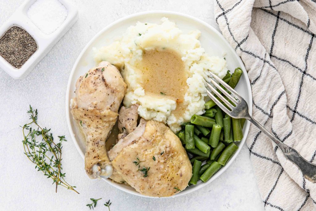 chicken and gravy plated with mashed potatoes and green beans.