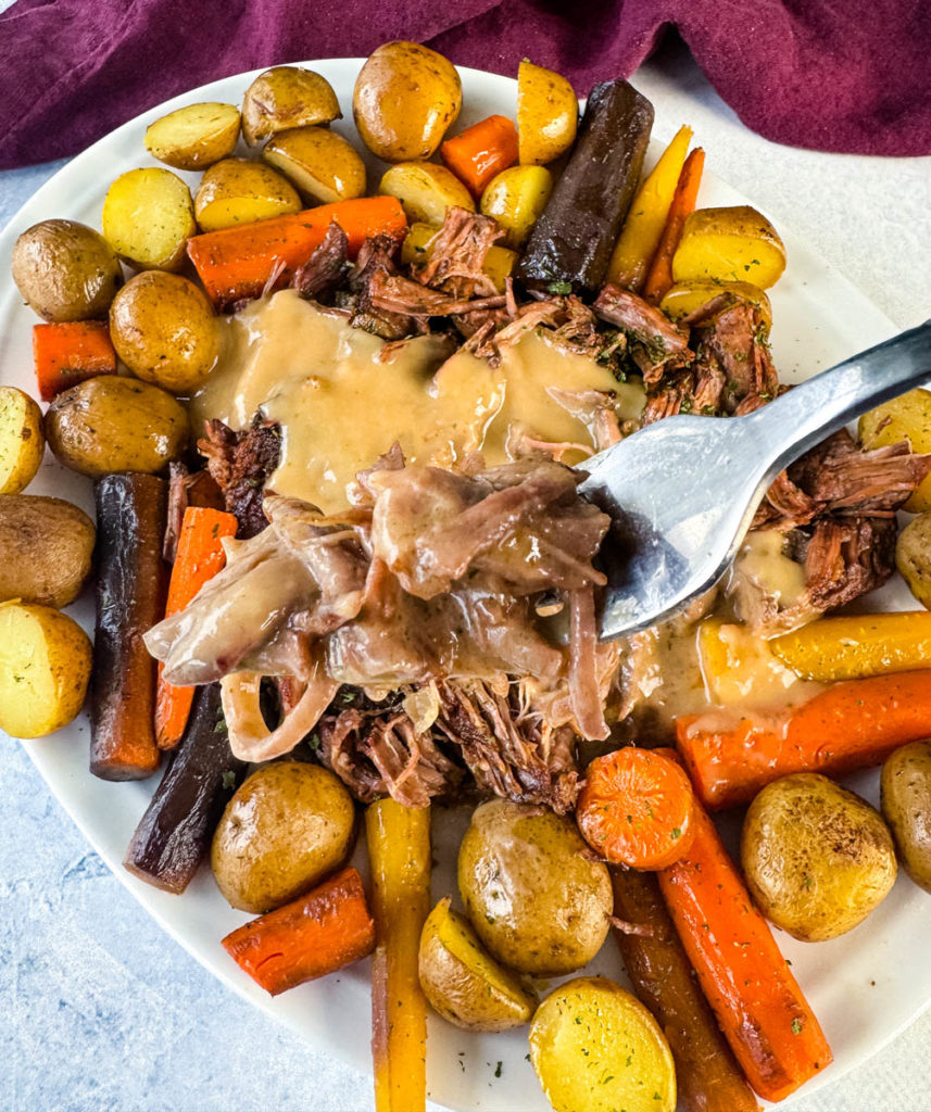 pot roast with carrots and potatoes on a platter and gravy