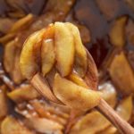 fried apples in skillet being raised up on spoon