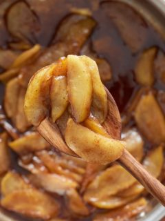 fried apples in skillet being raised up on spoon
