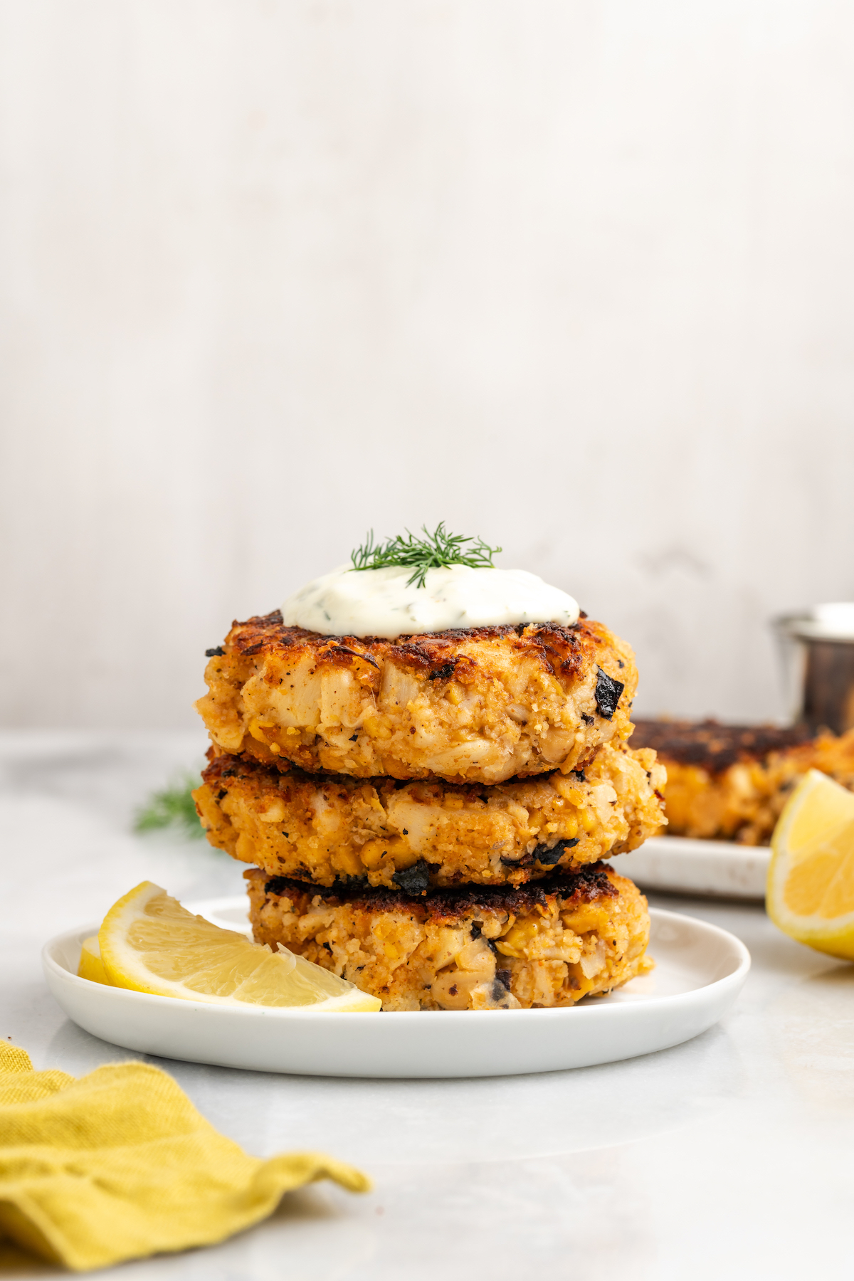 Stack of 3 vegan crab cakes topped with tartar sauce and dill