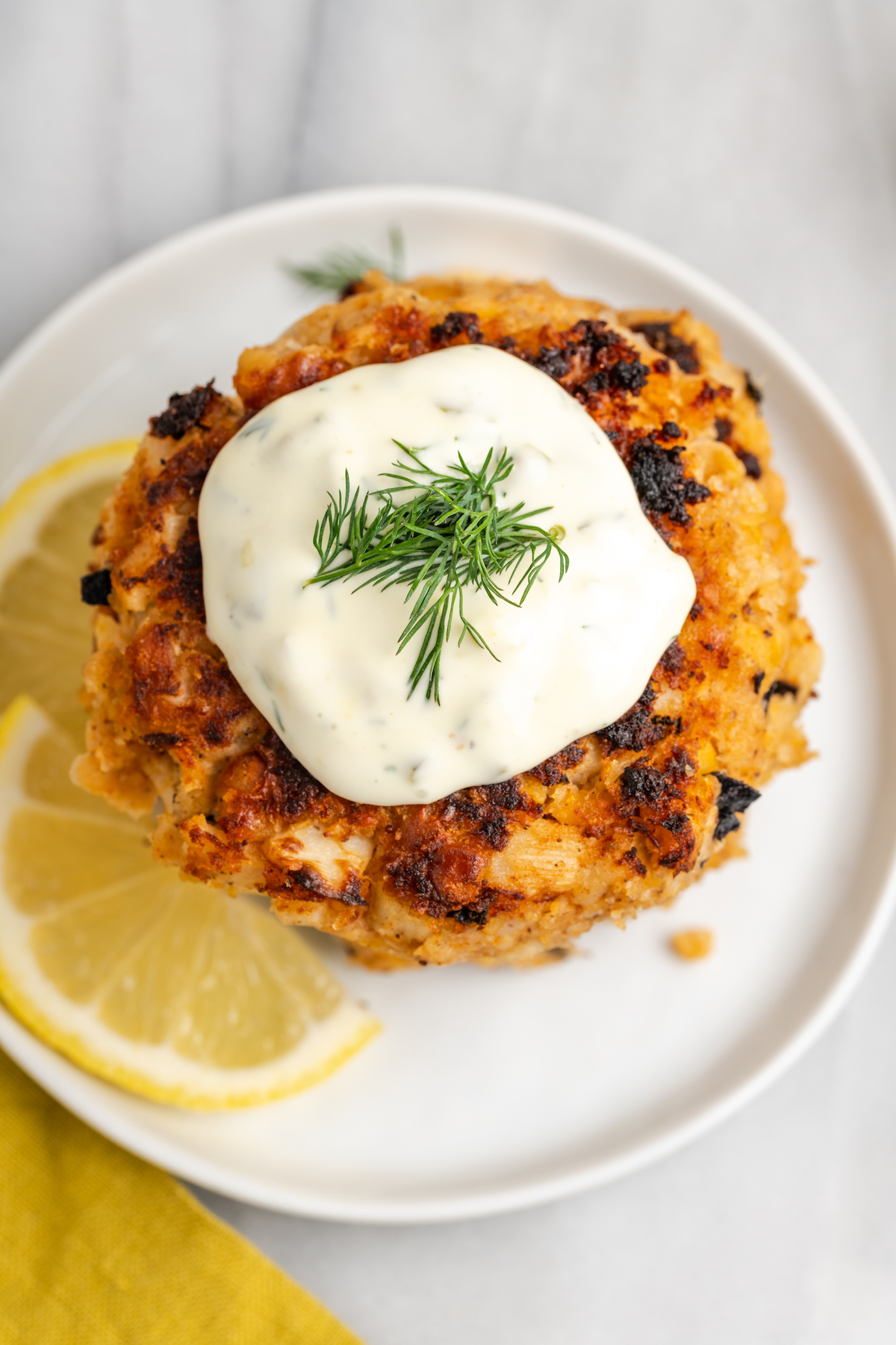 Overhead view of vegan crab cakes stacked on plate with tartar sauce