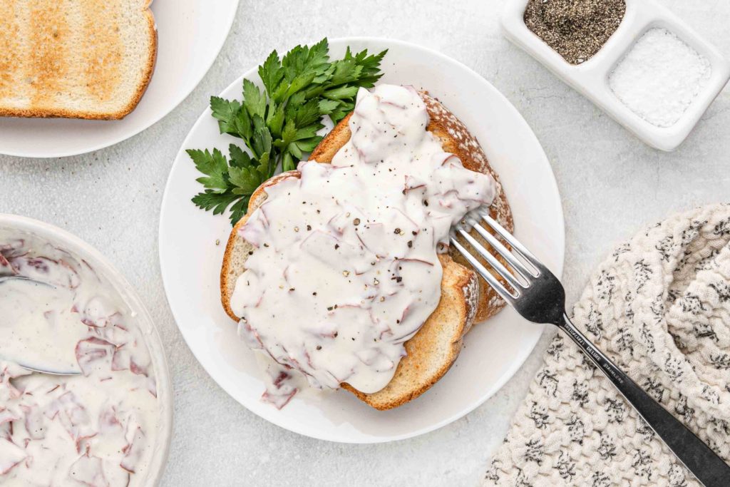 chipped beef gravy on toast, served on a plate.