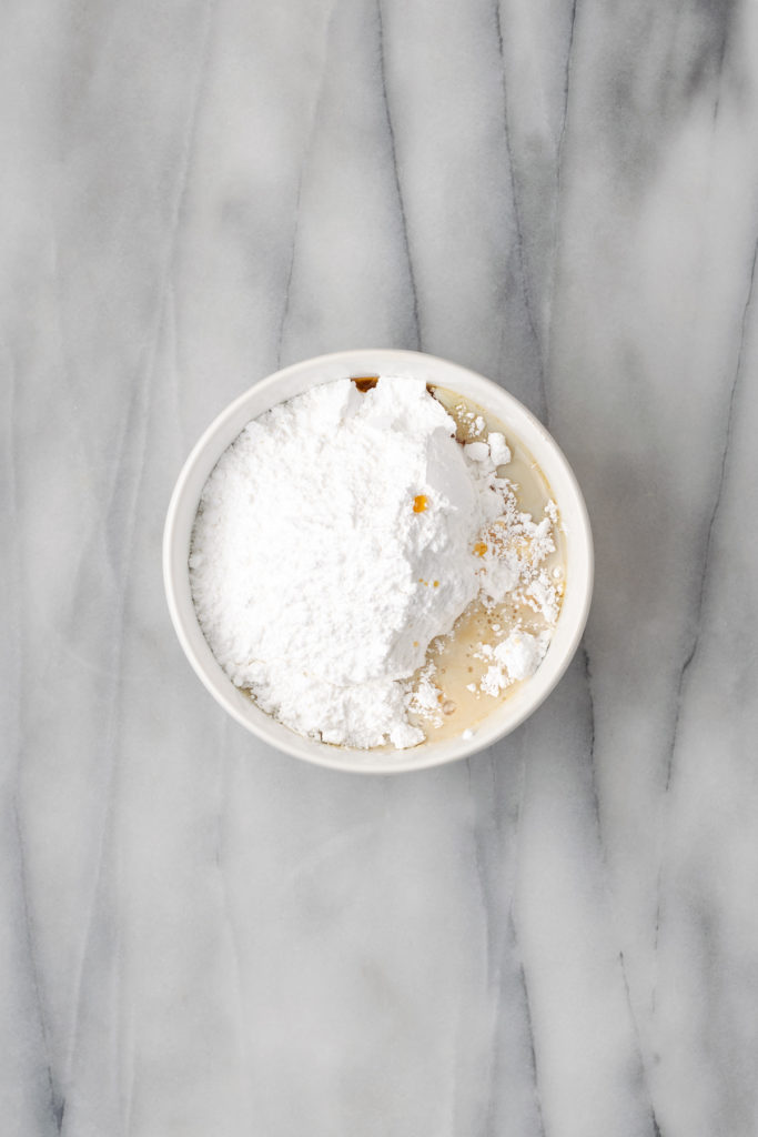 Overhead view of powdered sugar added to liquid ingredients for icing