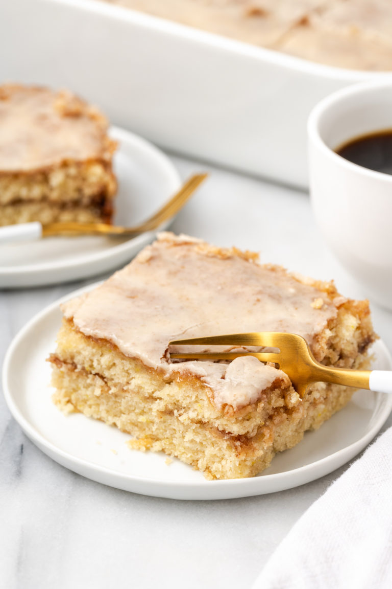 Serving of honeybun cake on plate with fork cutting into corner