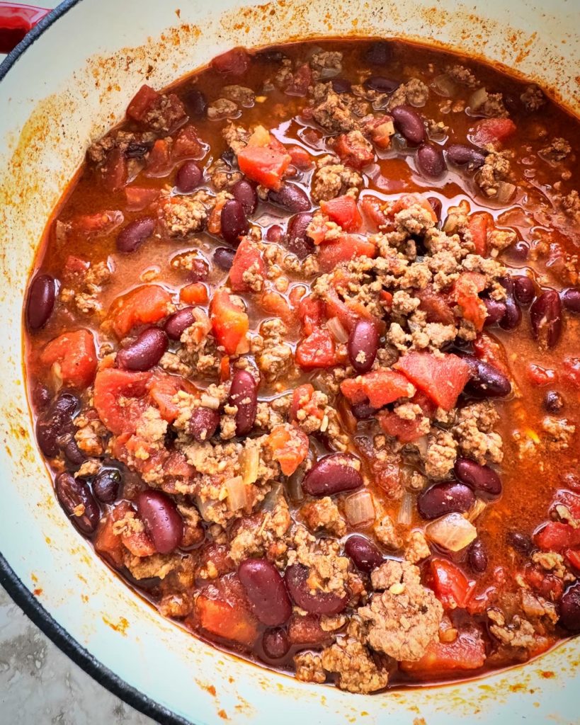 close up shot of beef chili in a white dutch oven