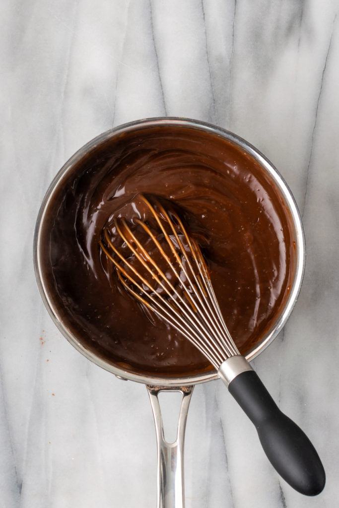 Overhead view of chocolate pudding mixture in pan with whisk