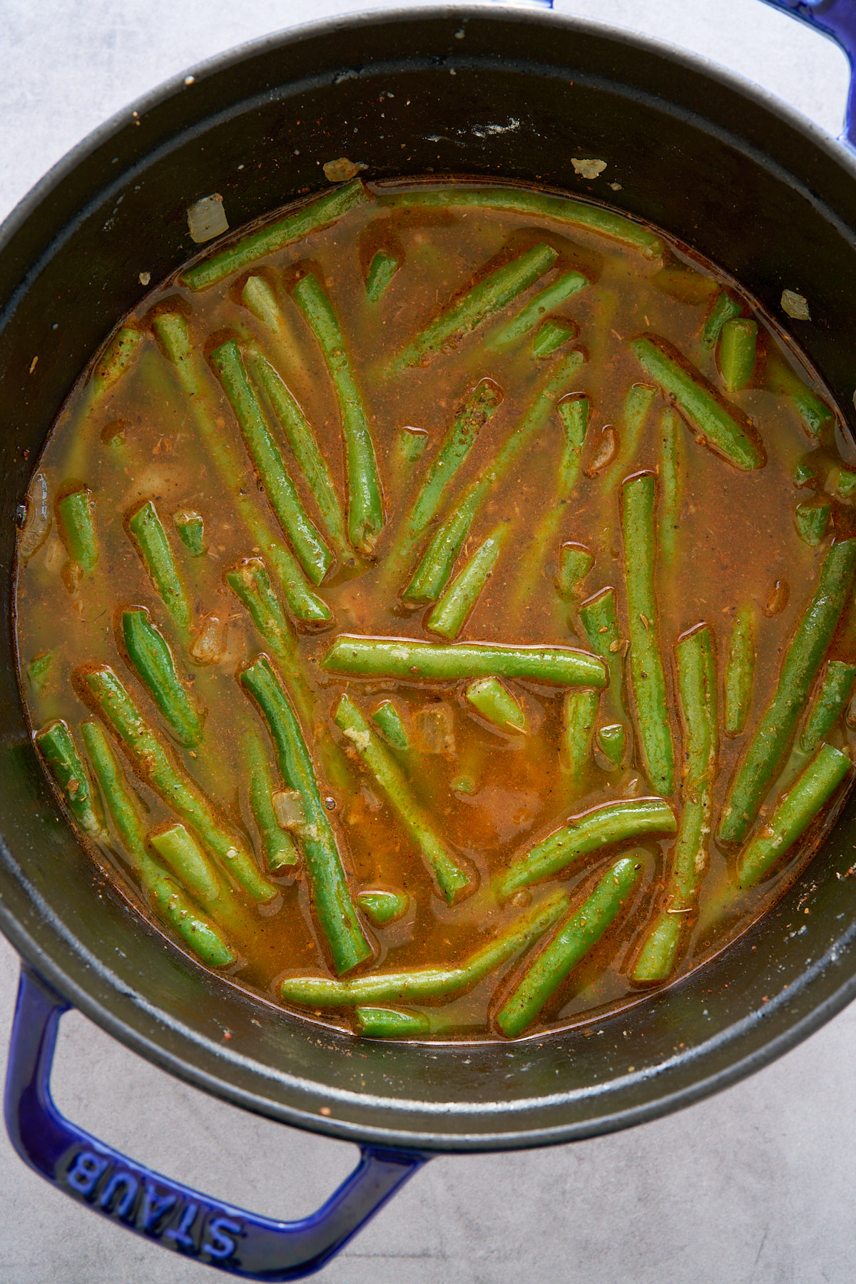 green beans in pot covered in broth and seasoning