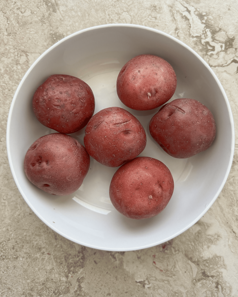 overhead shot of 6 red skin potatoes in a white bowl