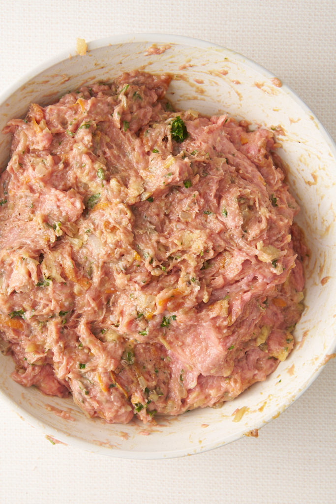 raw ground turkey meat with seasoning adding and mixed together