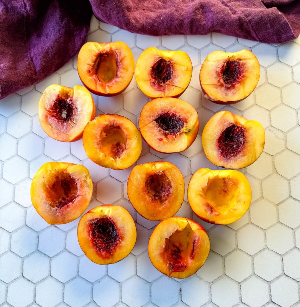 fresh peaches sliced in half on a flat surface