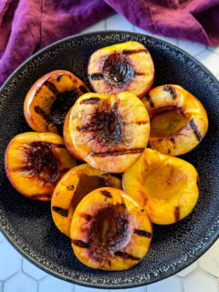 grilled peaches in a black bowl