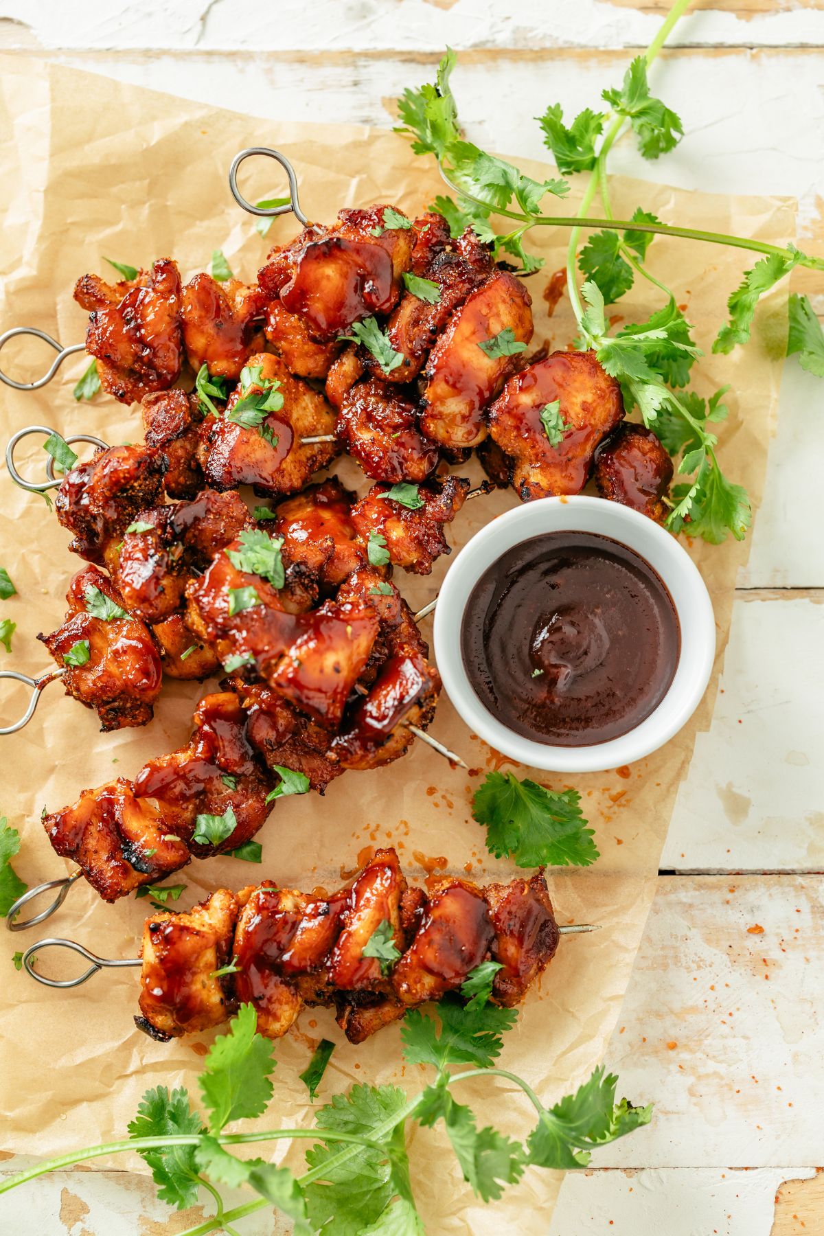 Air-fried chicken skewers with BBQ sauce for dipping, garnished with parsley.