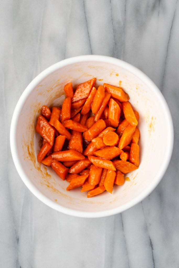 Overhead view of brown sugar glazed carrots in mixing bowl