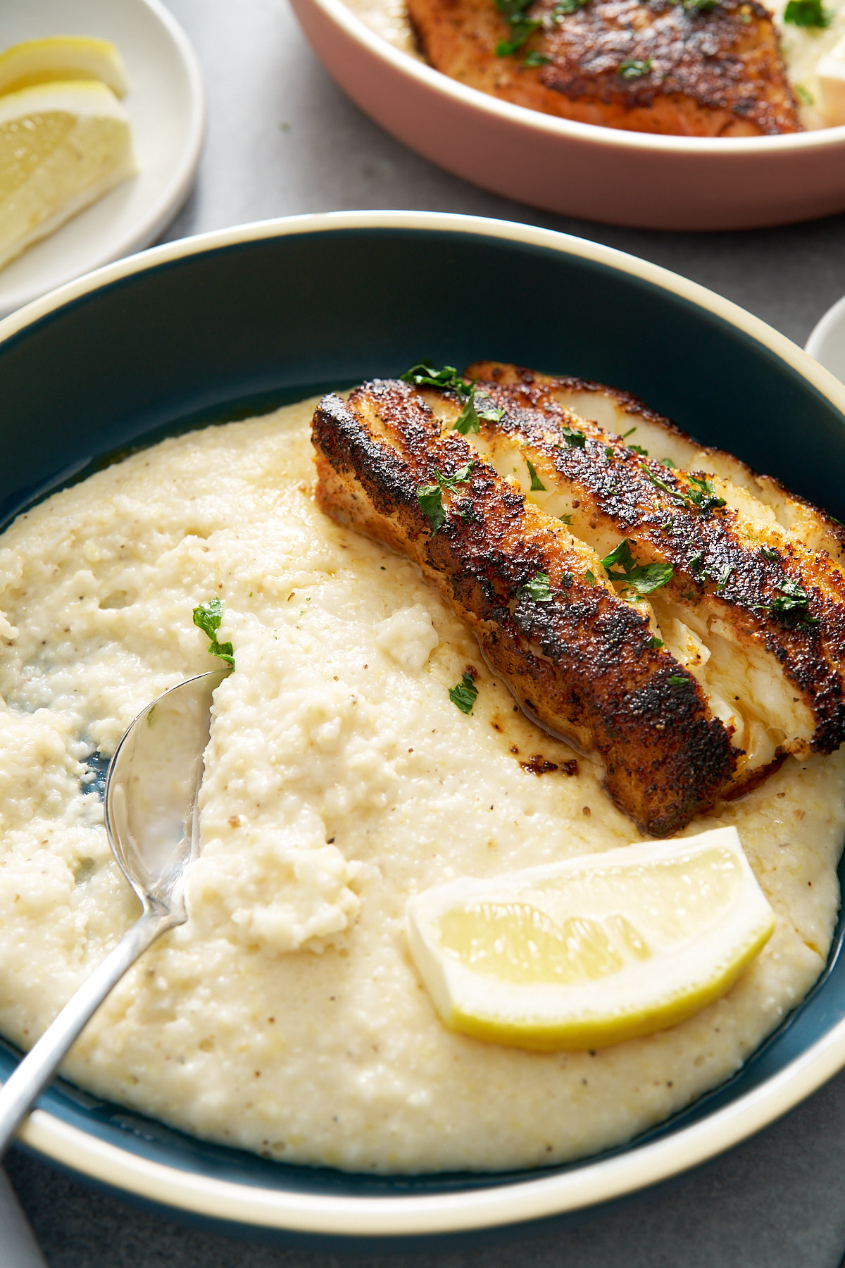 fish and grits on plate with spoon going into grits