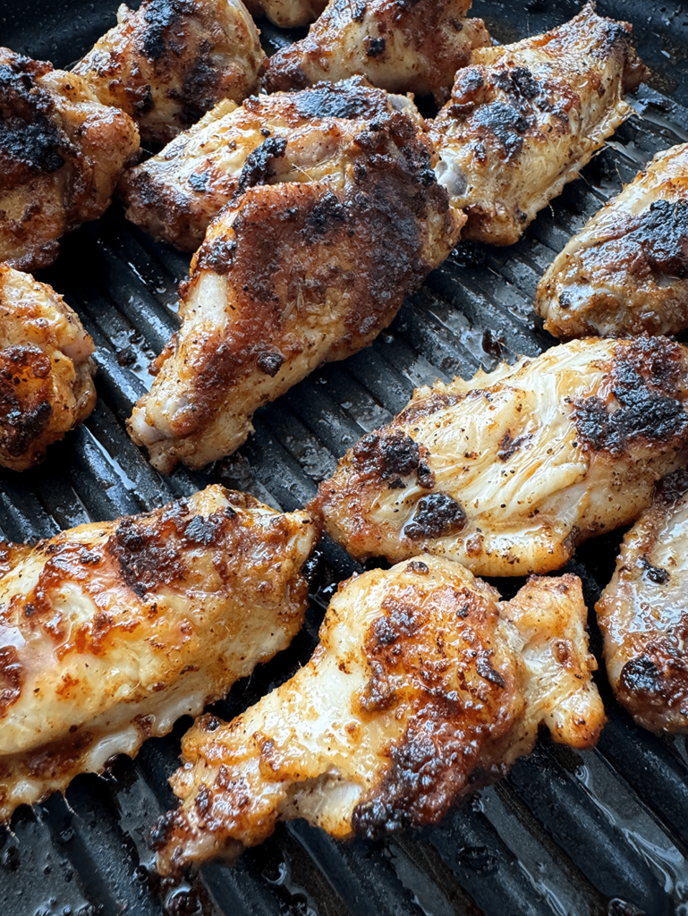 close up shot of chicken wings on a black grill