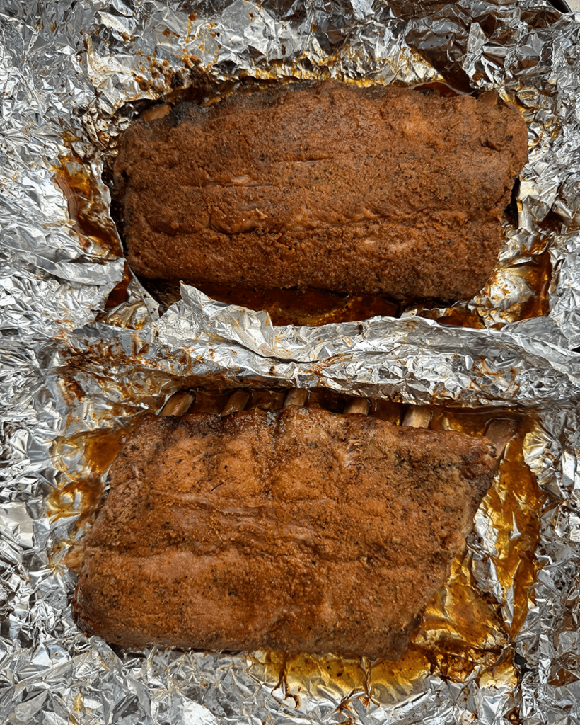 overhead shot of cooked, baked ribs on a sheet of foil