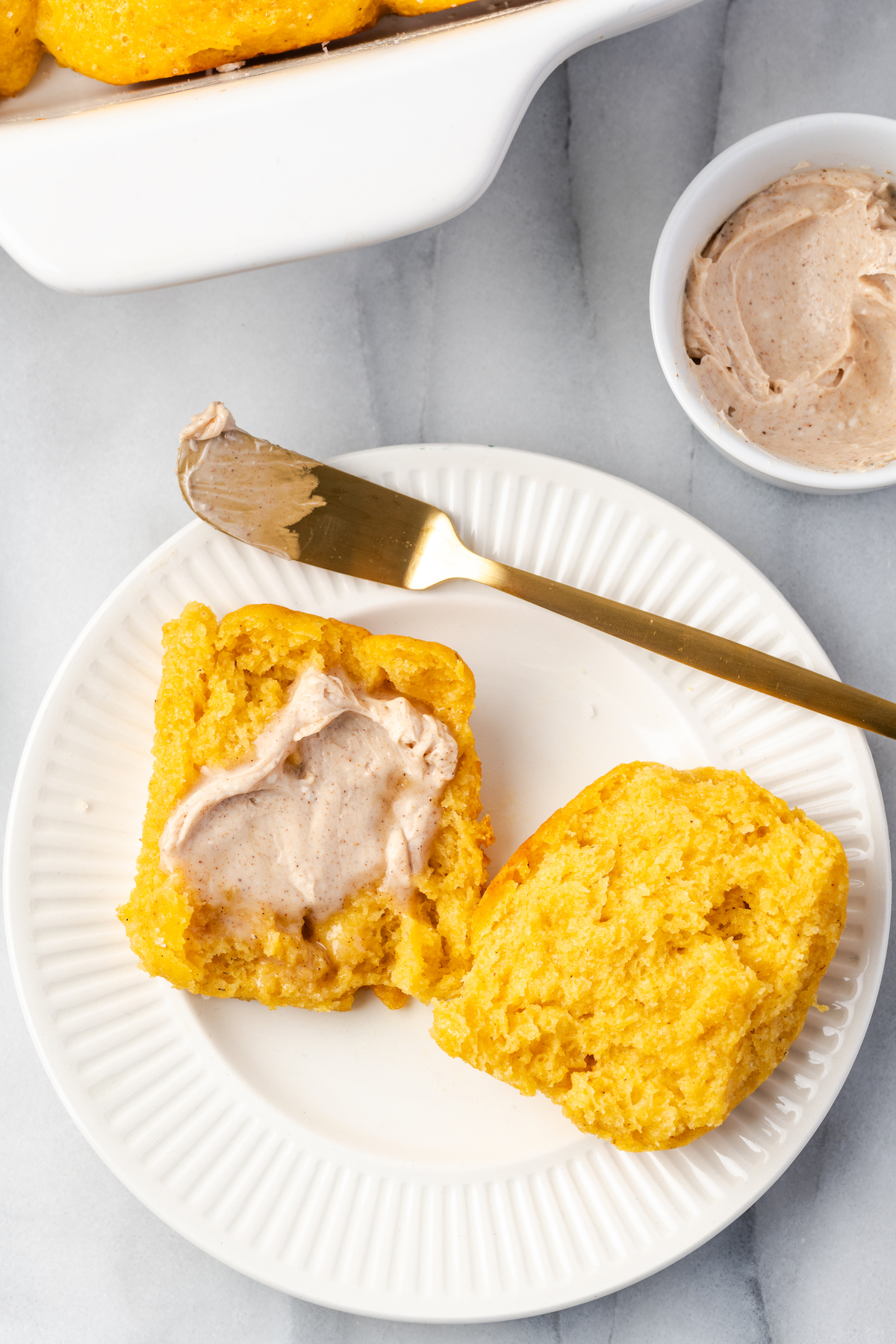 Sweet potato roll cut in half on plate with cinnamon butter spread on top