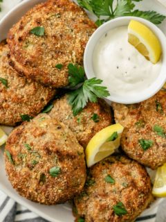 Golden-brown salmon patties with a creamy mayo dip on a plate.