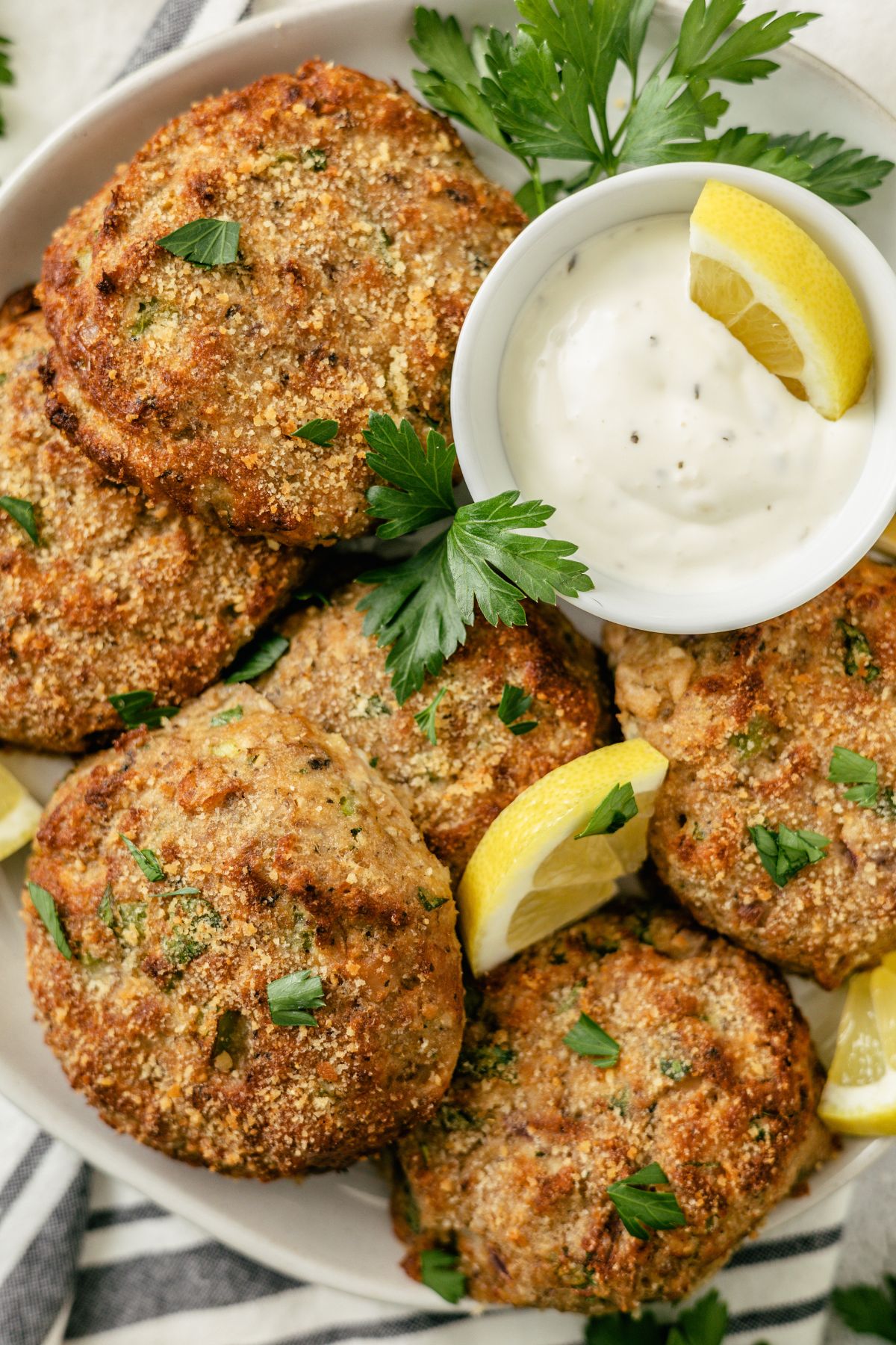 Golden-brown salmon patties with a creamy mayo dip on a plate.