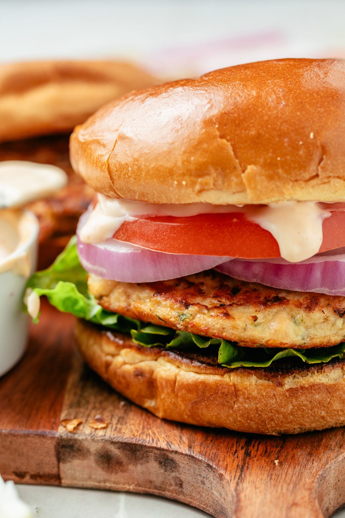 succulent salmon burger featuring crisp lettuce, juicy tomato slices, and a dollop of creamy sauce, served in a golden toasted bun