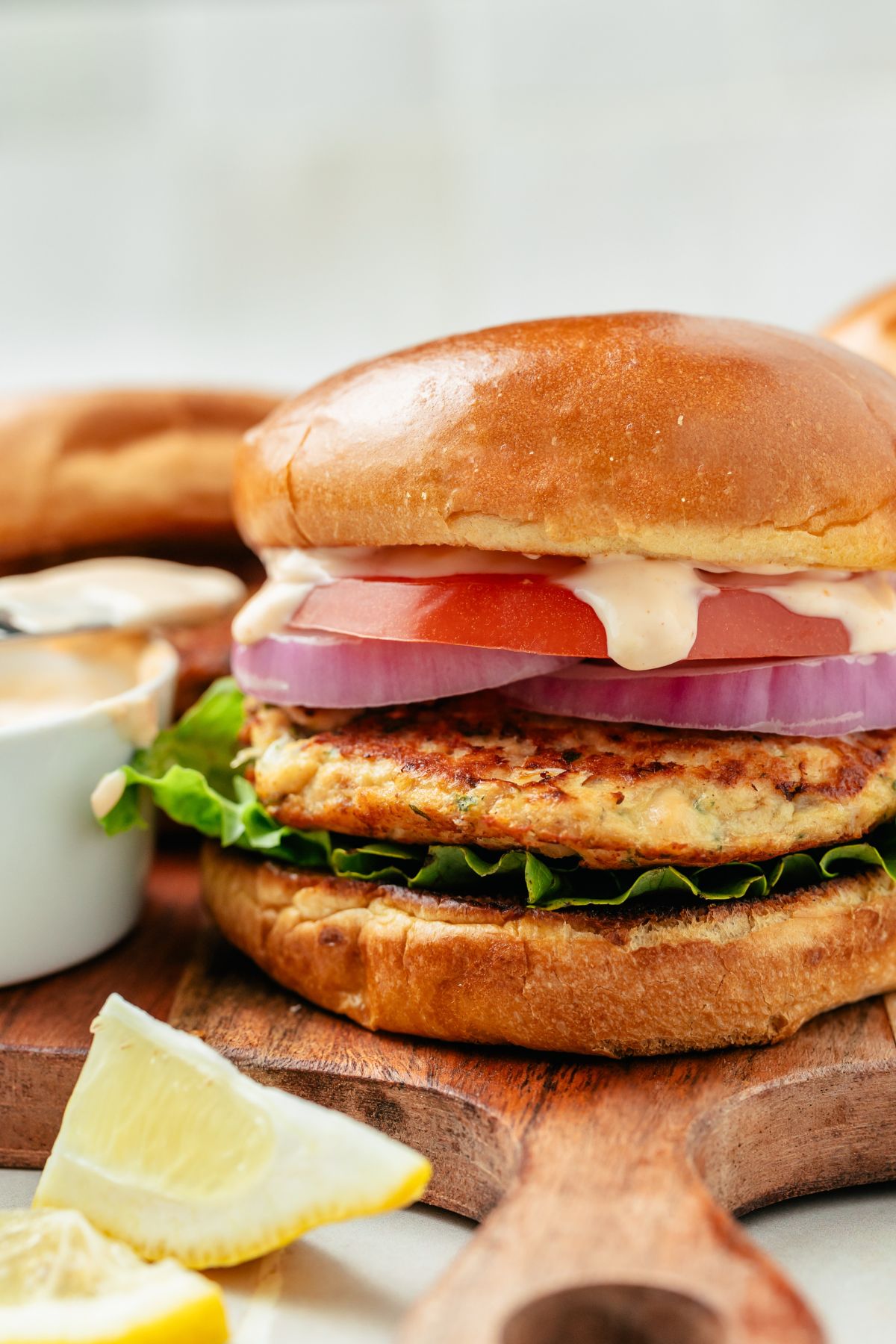 Image of a juicy canned salmon burger with fresh lettuce, ripe tomato slices, and a dollop of creamy sauce, all nestled in a perfectly toasted bun