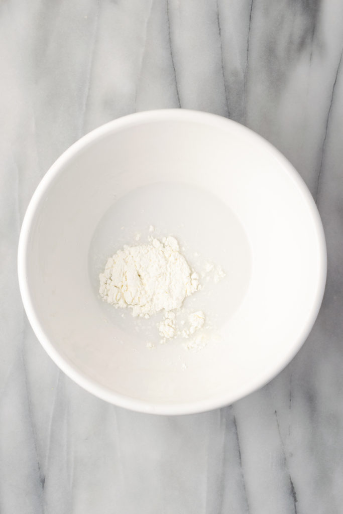 Overhead view of cornstarch and plant milk in bowl