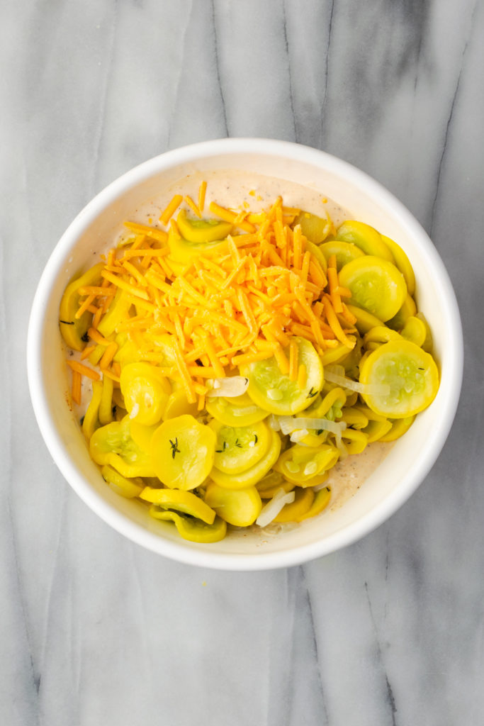 Overhead view of cheese and squash added to bowl of sauce